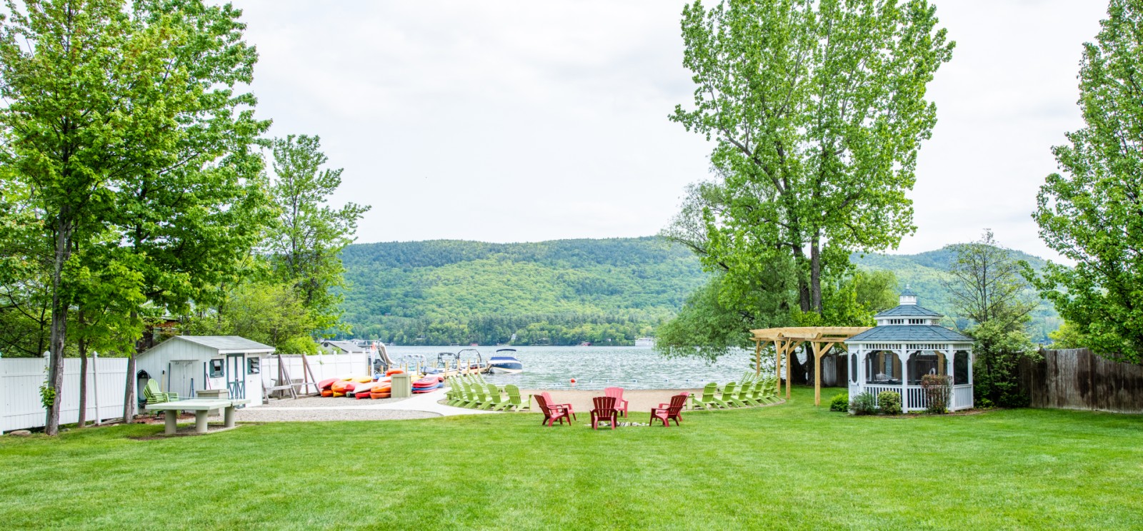 A grassy area with a gazebo, trees, and a lake in the background.