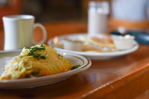 Omelet, pancakes, coffee mug on breakfast table