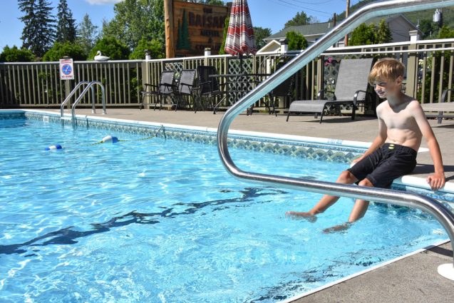 Little boy sitting on edge of swimming pool