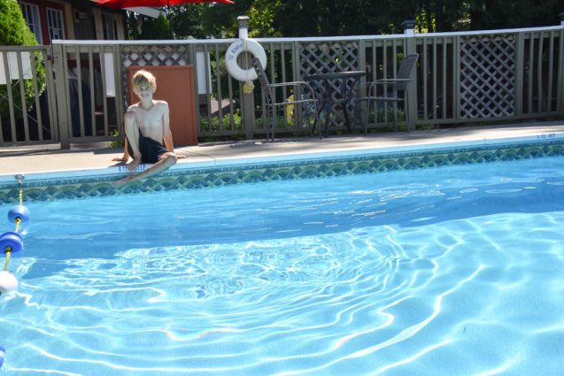 Little boy sitting on edge of outdoor pool